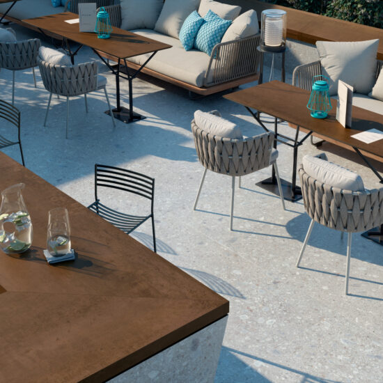 Pavimento in gres porcellanato chiaro con texture leggermente venata, ambientato in uno spazio esterno elegante e moderno.