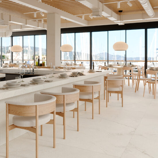 Rivestimento effetto pietra di tonalità neutra in un ristorante elegante con ampie finestre e arredi in legno chiaro.